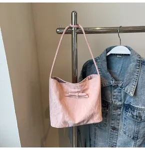Détail du sac cabas rose clair avec nœud décoratif suspendu à côté d'une veste en jean