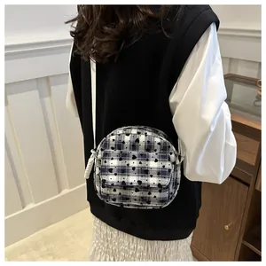 Close-up of black and white checkered saddle bag with heart detail worn by a model