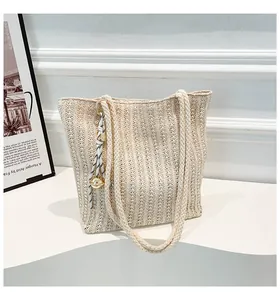 Detailed macro view of woven straw tote bag texture with decorative metallic ball charm