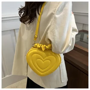 Bright yellow heart-shaped crossbody bag worn with a beige corduroy suit for winter