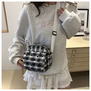 Detail of plaid crossbody bag with heart prints and adjustable white shoulder strap