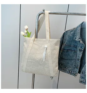 Texture détaillée du cabas en paille tissée beige avec pompon blanc et accent de tulipe