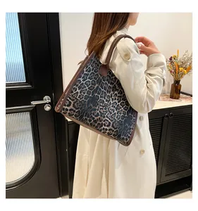 Detail der Leopard-Tasche mit braunen Ledergriffen, getragen über einem beigen Trenchcoat