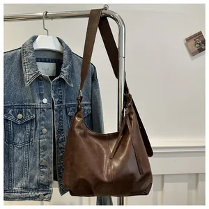 Detail einer braunen Vintage-Hobo-Tasche mit dekorativen Seitentroddeln und Nähten