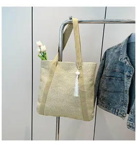 Détail du sac cabas en paille beige clair avec texture tressée, anses et pompon blanc