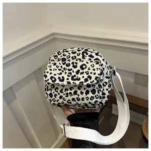 Detail view of canvas crossbody bag featuring black white leopard print and front pocket