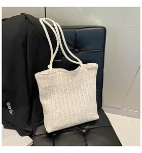 Close-up of cream woven straw tote bag texture leaning against a black sofa
