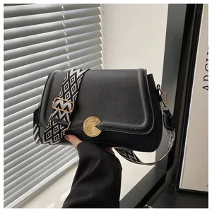 Close-up of black lychee grain leather bag with geometric pattern wide strap and gold buckle