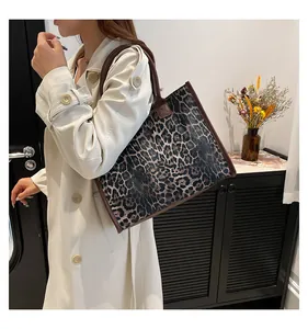 Lifestyle-Foto der Leopard-Tragetasche mit braunen Ledergriffen und lässigem Trenchcoat