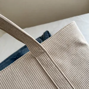 Detail view of durable stitching and corduroy texture on the beige tote bag handle