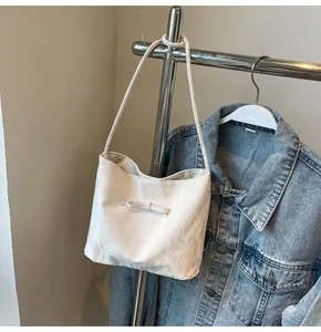 Détail du sac cabas blanc avec nœud décoratif et texture plissée sur cintre en métal