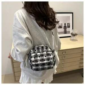 Detail of checkered crossbody bag with black heart patterns and white shoulder strap