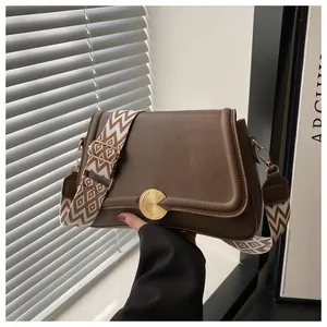 Detail of dark brown lychee grain leather handbag with gold snap and geometric strap