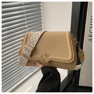 Detail of lychee pattern leather texture and gold circular twist-lock on a khaki bag