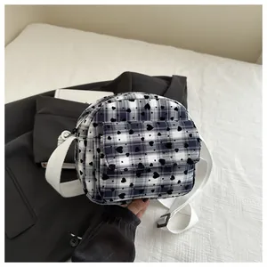 Detail of checkered heart crossbody bag with front flap pocket and adjustable wide strap
