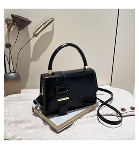 Detail of a textured black leather handbag featuring a large buckle and gold hardware
