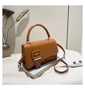 Detail of a brown leather crossbody handbag with square buckle on vintage books