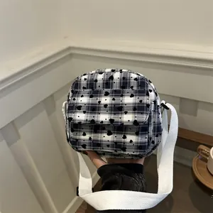 Chic plaid crossbody saddle bag with black hearts and a wide white woven strap