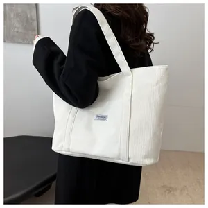 Detail of the corduroy texture and fashion label on the large off-white tote bag