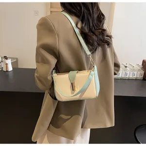 Detail of stylish two-tone faux leather shoulder bag with golden metallic twist lock