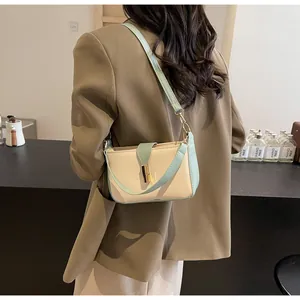 Model wearing cream and mint green crossbody bag with gold buckle over shoulder
