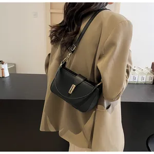Detail view of the black matte shoulder bag with a gold buckle on a stylish model
