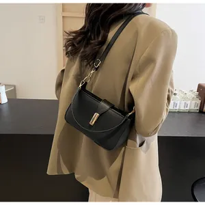 Detail of minimalist black leather underarm bag with gold lock on beige blazer outfit