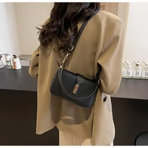 Detailed back view of a model wearing a black minimalist crossbody bag with metal lock
