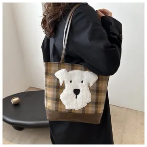 Close-up of checkered tote bag featuring plush dog patch and faux leather bottom detail