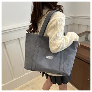 Close-up of the grey corduroy tote bag showing the wide strap and FASHION INSTINCT label