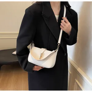 Close-up of beige leather shoulder bag featuring elegant golden metal twist lock and stitching