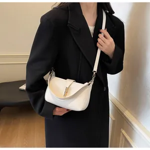 Detail shot of a white leather crossbody bag with elegant gold metal buckle on a black coat
