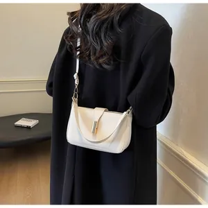 Detail of off-white minimalist shoulder bag with gold metal buckle on model's back