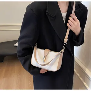 Close-up of a two-tone crossbody bag with white and khaki panels and a gold metal clasp