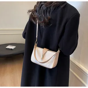 Detail view of the khaki strap and gold metal clasp on a bicolor crossbody bag