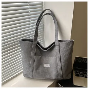 Detail of grey corduroy tote bag featuring an outer pocket and white textile label
