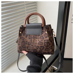 Detail of leopard print suede tote with resin handle, leather flap and gold rivets