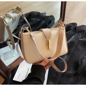 Detailed shot of beige and brown crossbody bag with gold buckle and adjustable strap