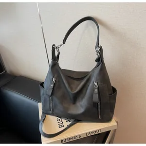 Detail of black faux leather tote bag featuring dual front zipper pockets and wide shoulder strap