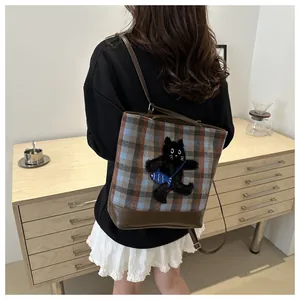 Detail of checkered shoulder bag with cute black plush cat embroidery and leather base