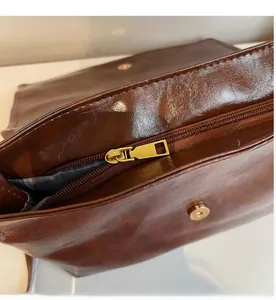 Detail of smooth gold zipper and magnetic closure on brown faux leather bag