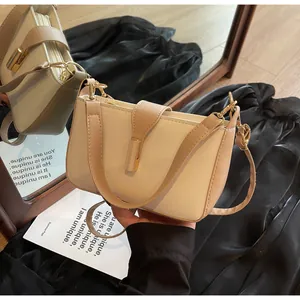 Detail of a structured cream and brown crossbody bag with a gold rectangular metal lock