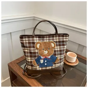 Detail of checkered tote bag featuring a cute teddy bear embroidery and leather straps