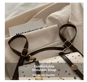 Detail view of colorful polka dot handbag with comfortable brown leather shoulder strap