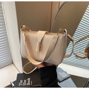 Detail view of a beige rectangular leather shoulder bag with gold clasp and dual straps
