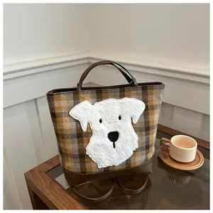 Detail of plaid tote bag featuring a cute white plush cartoon dog patch and leather handle
