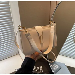 Detail of cream leather shoulder bag featuring a prominent gold metal clasp and wide strap