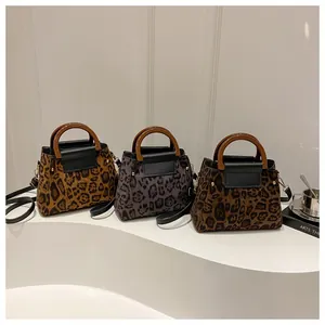 Detailed view of three leopard print shoulder bags in light brown, grey purple and dark brown