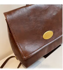 Macro shot of brown pebble grain faux leather and gold metal nameplate on the backpack