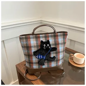 Detail view of plaid tote bag featuring a cute cat plush patch with blue fish decoration